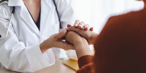 A man holding his neck in pain near damaged cars